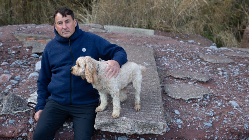 Richard, with him arm around small dog on the beach