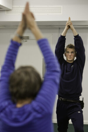 Yoga in prison: a teacher and officer with arms above heads in a yoga pose.