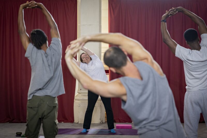 Back view of men in grey sweatshirts and joggers with arms raised and bending to side