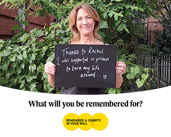 Brown-haired woman standing in front of tree holding a chalkboard stating "Thanks to Rachel I was supported to turn my life around in prison"